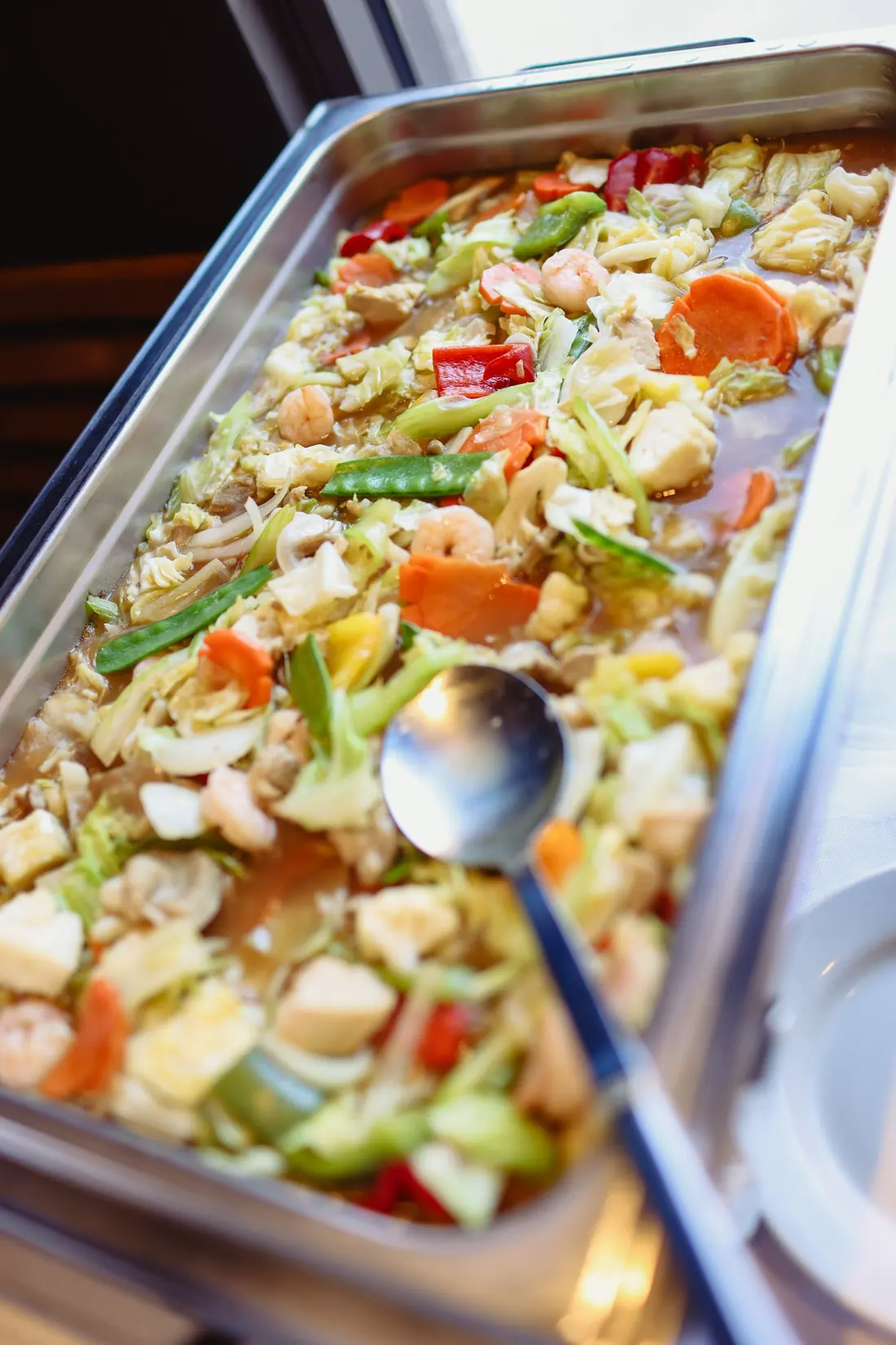 A chafing tray of chopsuey with shrimp, carrots, snow peas and cabbage