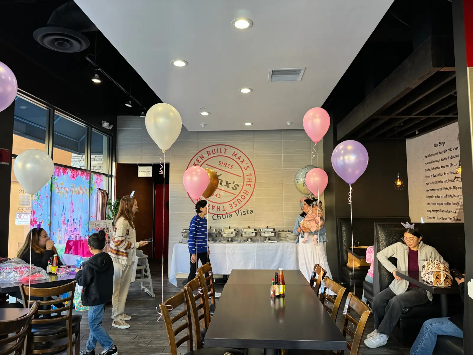 A princess-themed Happy Birthday backdrop by the window, balloons tied to the tables and a buffet under the Max's wall sign at Max's Chula Vista