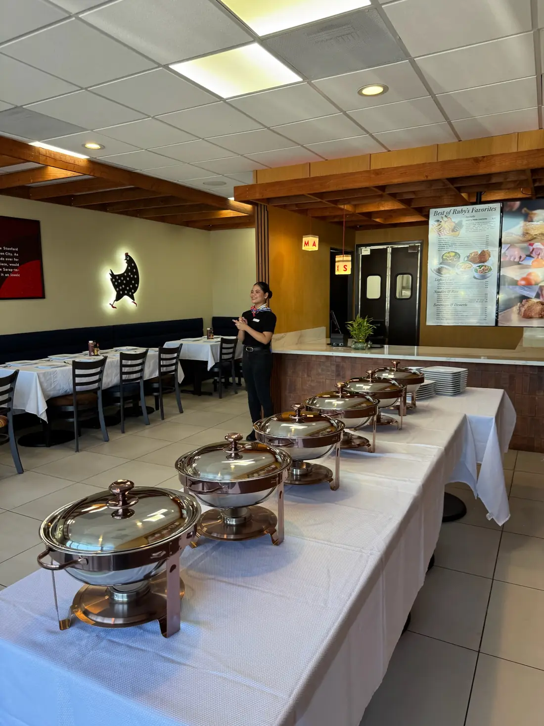 A smiling Max's host stands beside the buffet line of copper-tone chafing dishes near the counter at Max's National City