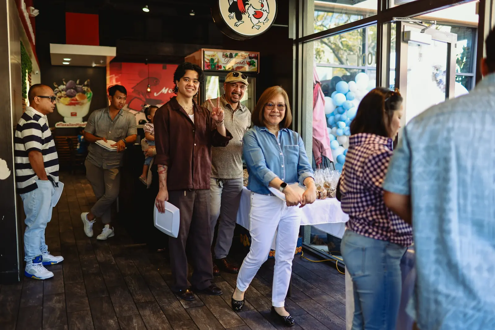 Guests holding plates line up for the buffet inside Max's Chula Vista, with blue and white balloons by the door