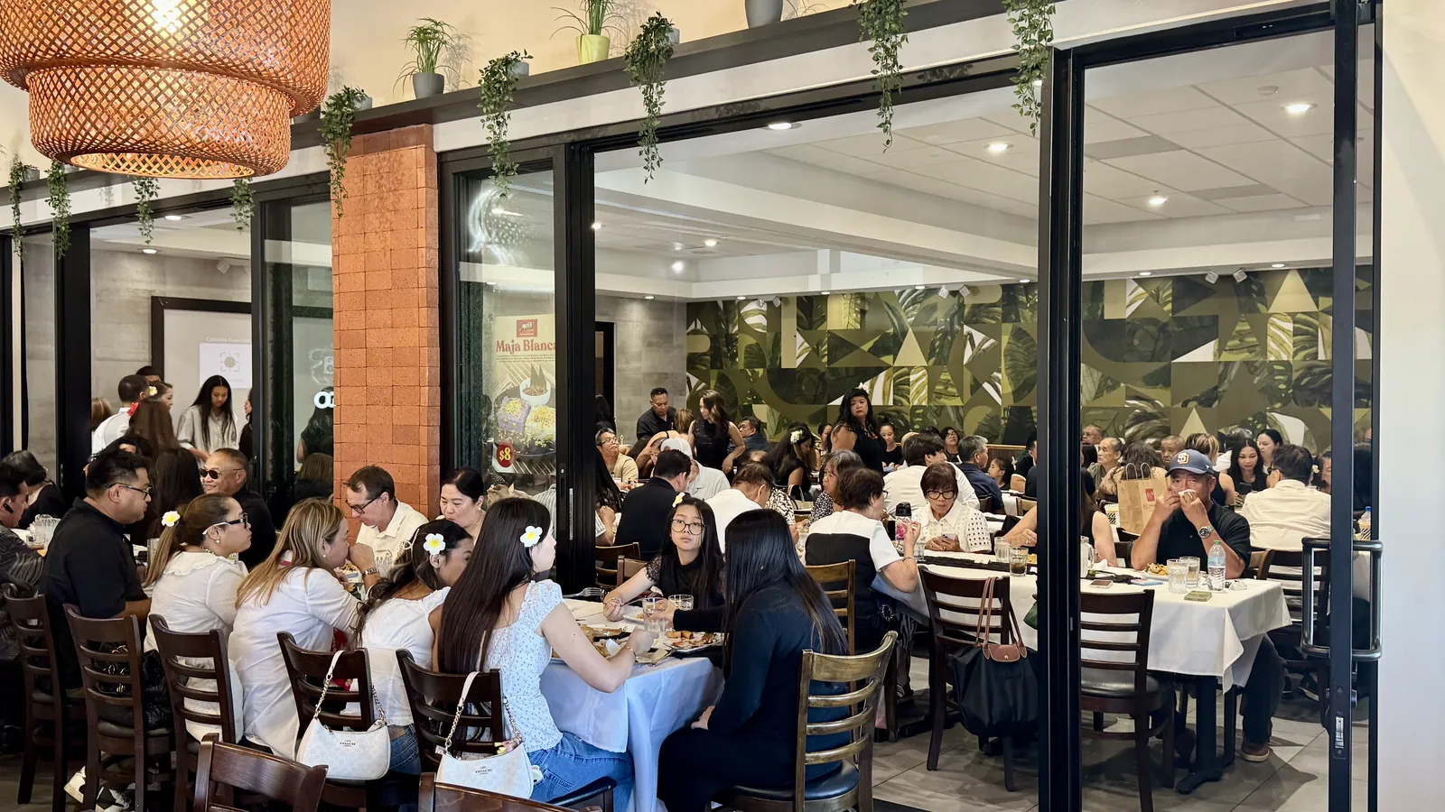 A celebration underway behind the glass doors of the Max's San Diego dining room, with the green leaf mural on the back wall