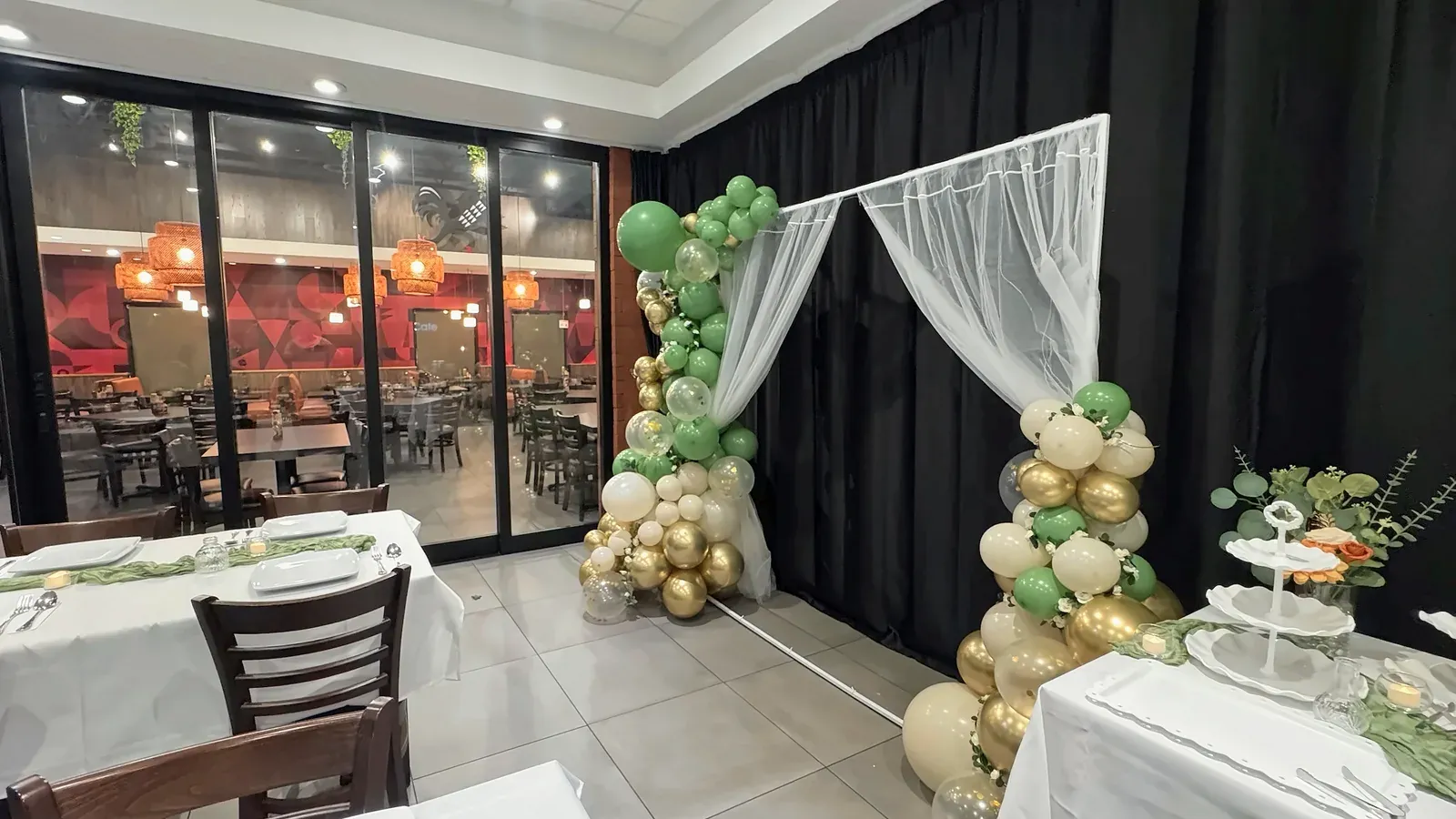 A balloon arch with a sheer curtain beside the glass doors that look out to the main dining room at Max's San Diego