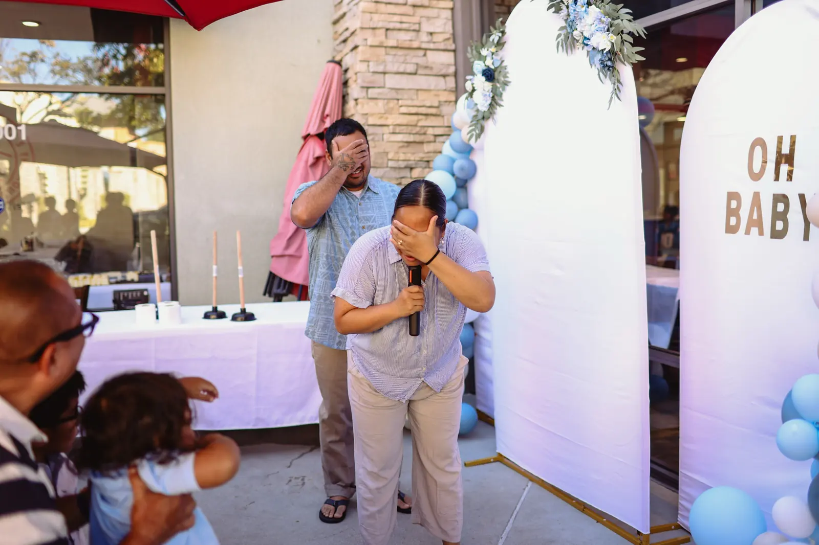 Guests laugh through a shower game on the Max's Chula Vista patio, beside the Oh Baby arch